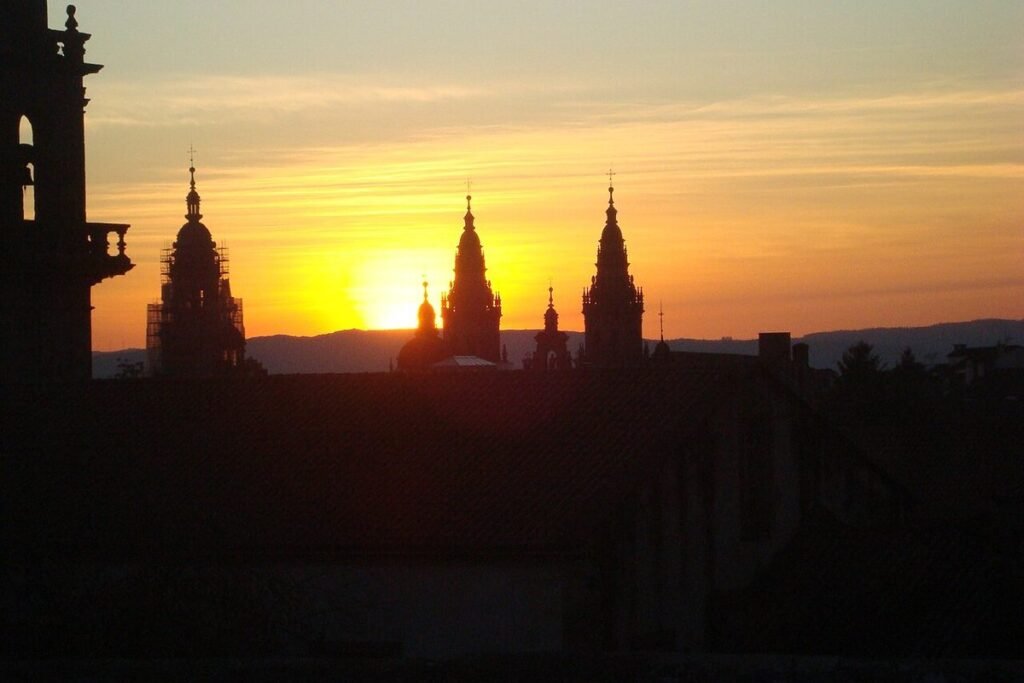 Silhouette des tours de la cathédrale de Saint-Jacques-de-Compostelle sur un ciel orangé au coucher du soleil