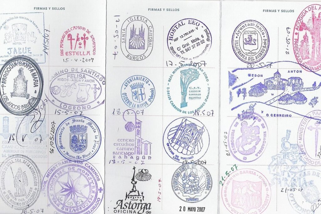 Pages d'une crédenciale de pèlerin couvertes de tampons colorés des étapes du chemin de Saint-Jacques, dont Astorga