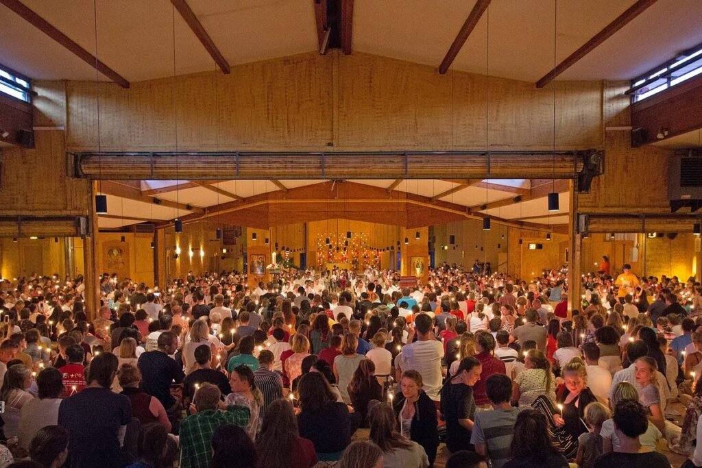 Foule de jeunes assis dans l'église de la Réconciliation de Taizé pendant une prière aux bougies